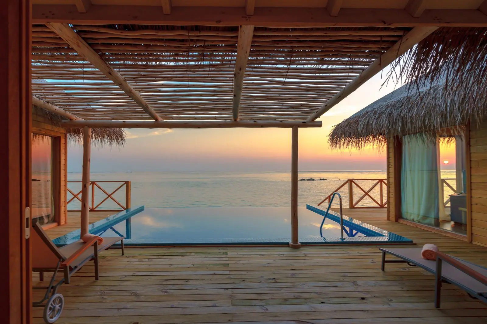Villa deck and plunge pool looking out over a calm sea at sunset
