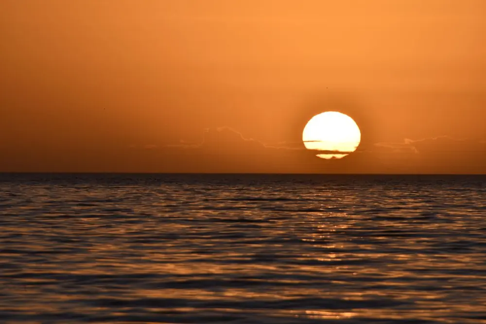 Sunset over a calm sea with golden light reflecting on the water